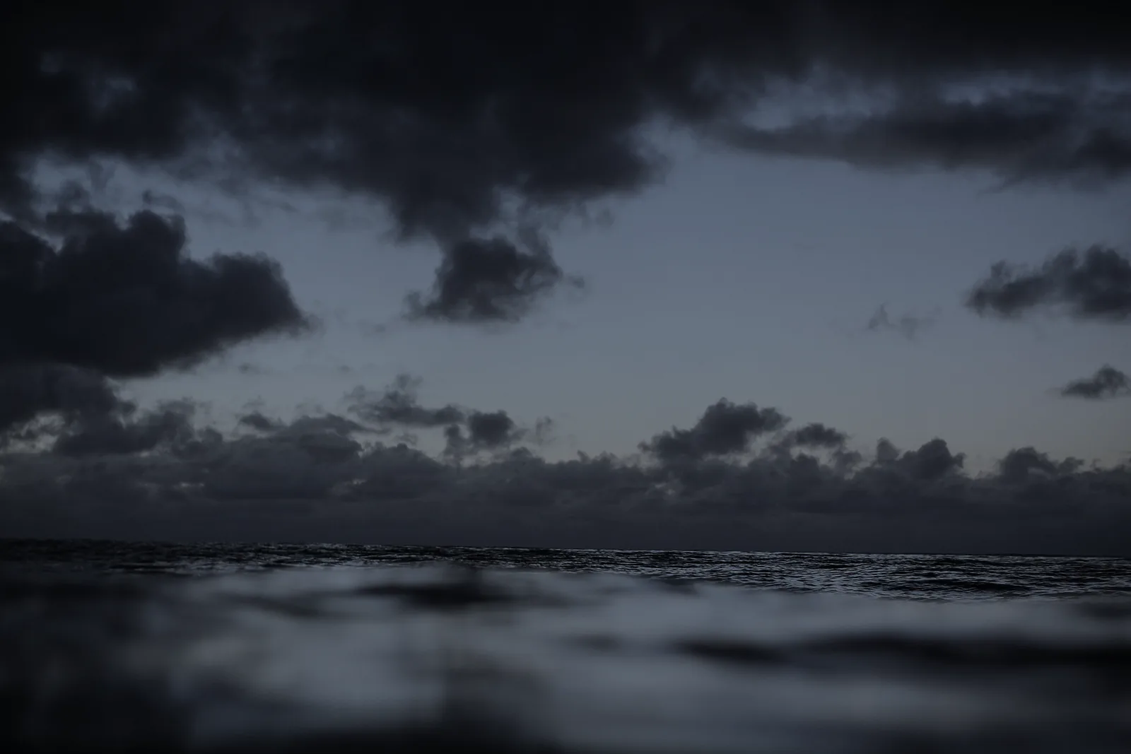 Dark cloud bank over open water at dusk