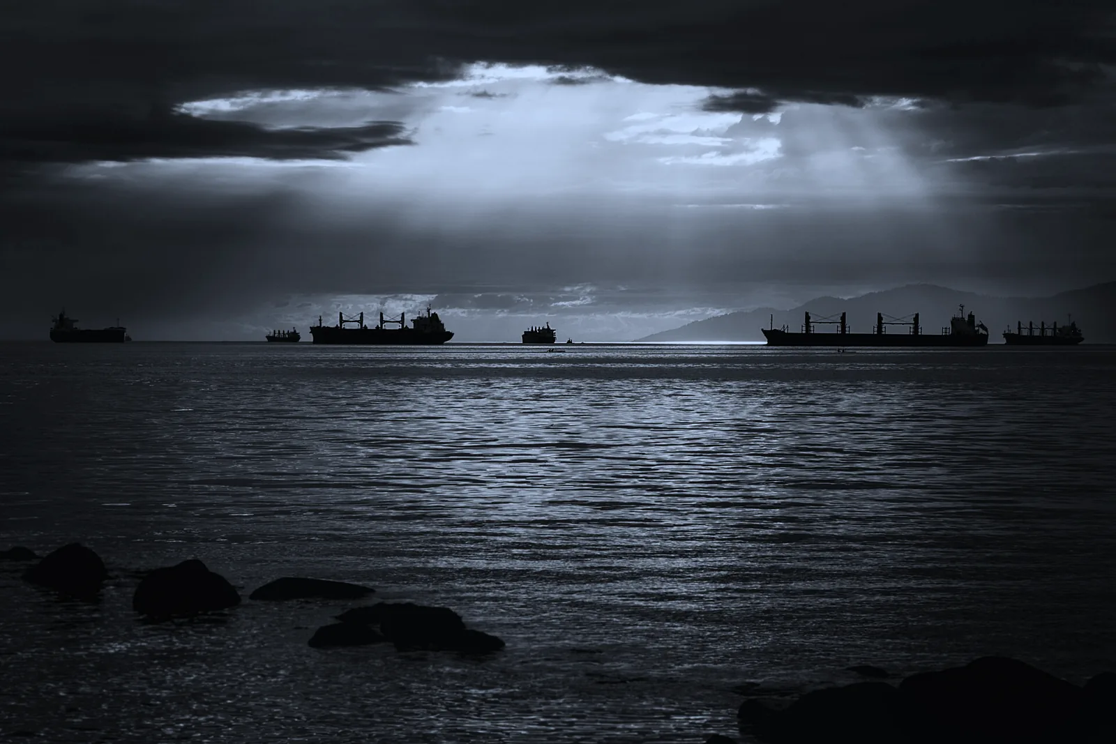 Anchored ships on the horizon under a break in the cloud